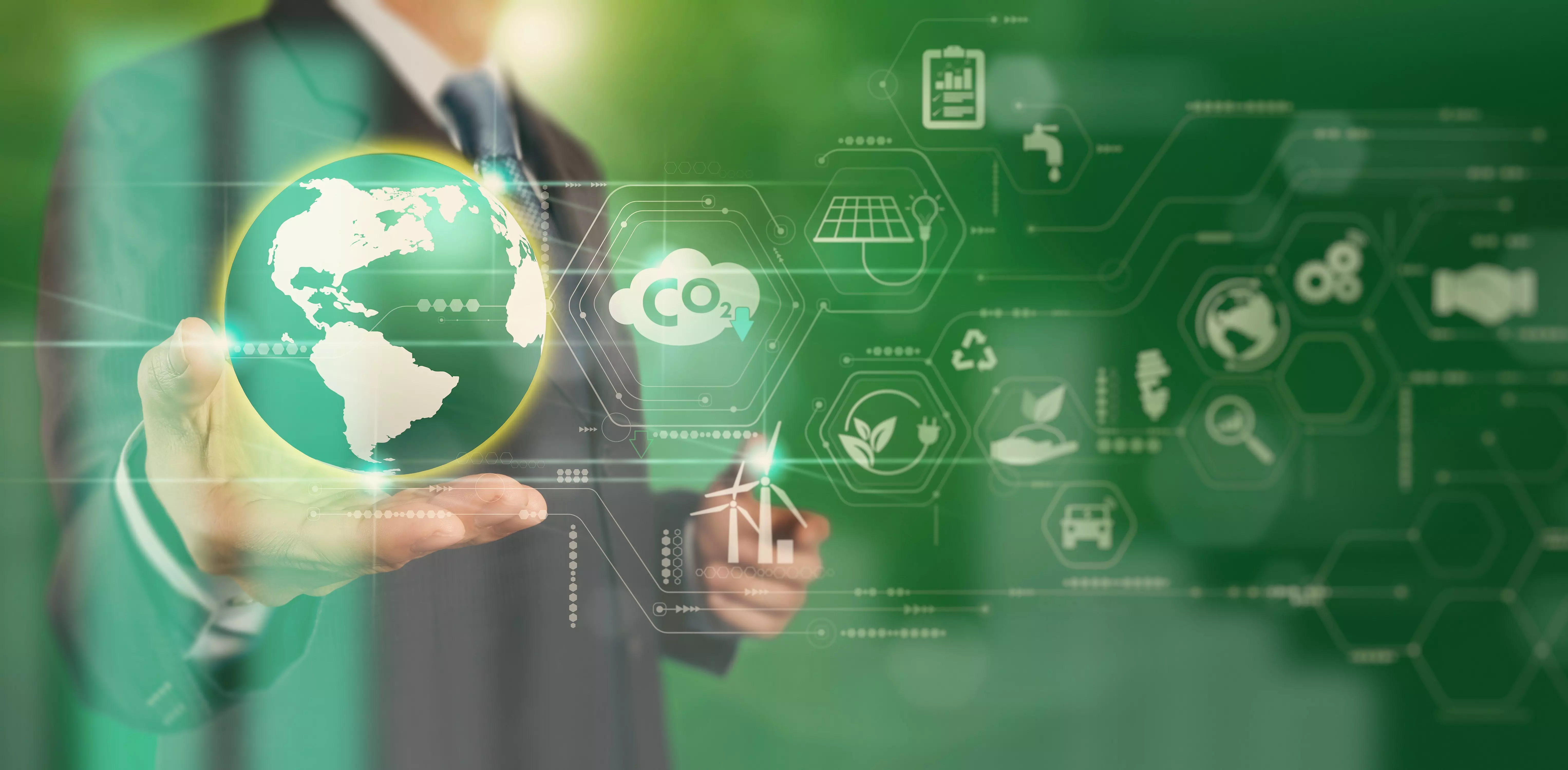 Mann in Anzug mit Weltkugel in der Hand vor grünem Hintergrund und diversen Umwelt- und Energiesymbolen
